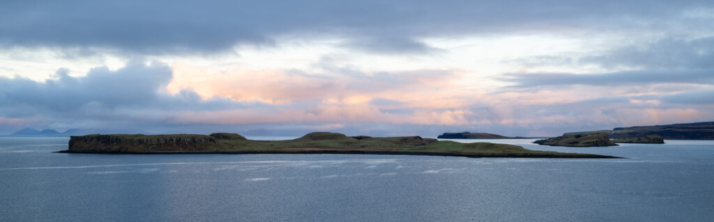 Küste in Schottland bei Sonnenaufgang mit farbigen Wolken